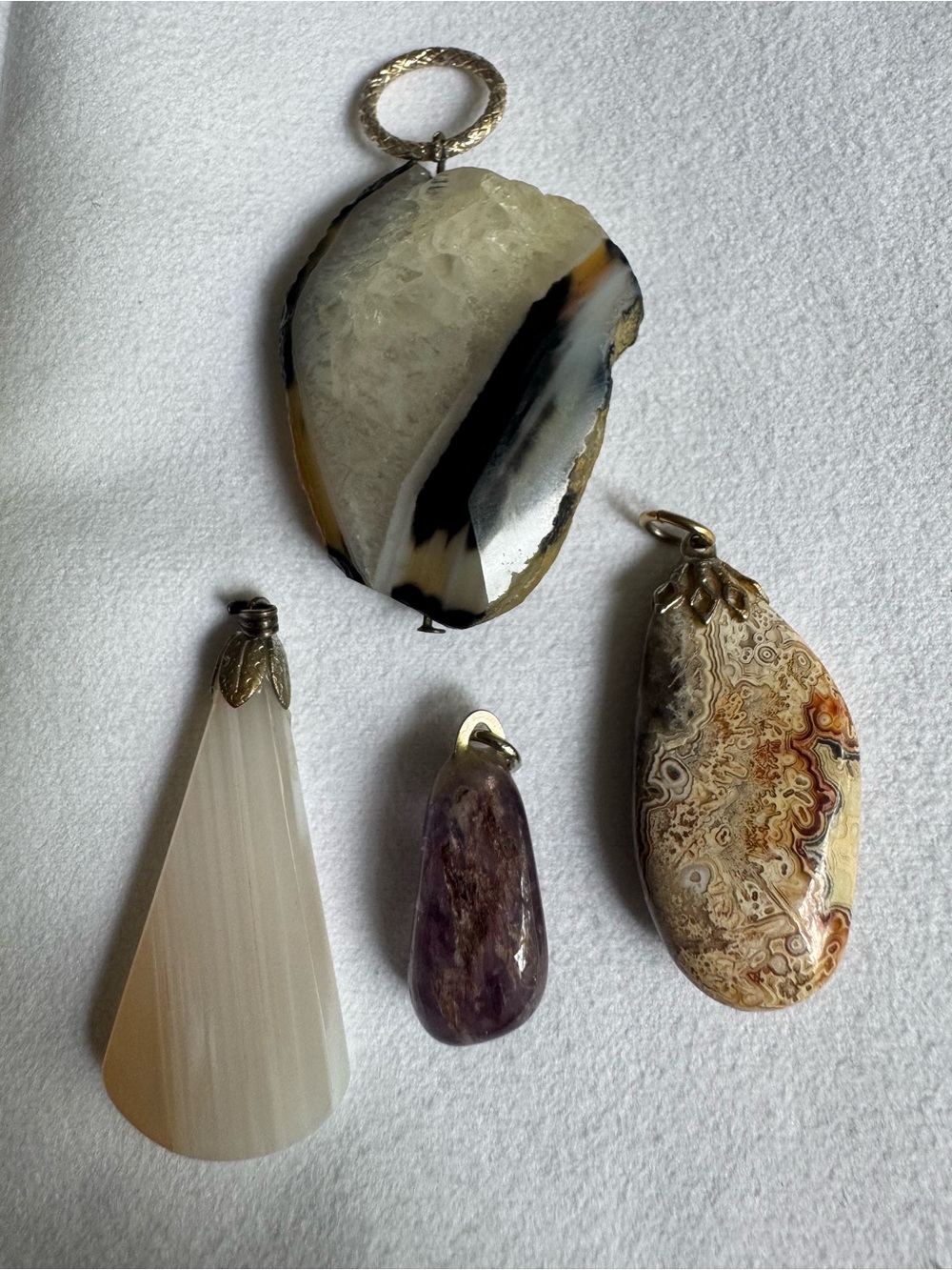 Four pendants. Agate, selenite,Charoite